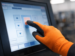 Industrial operator using a glove-compatible touch screen on a factory HMI
