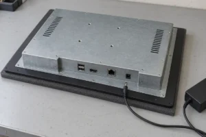 Rear view of an industrial panel PC with a disconnected DC power plug on a service bench
