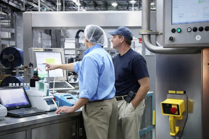 Operadores que utilizam um sistema de controlo com ecrã tátil industrial numa unidade de transformação alimentar
